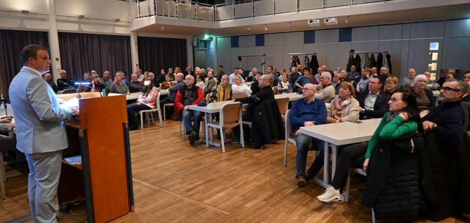 Bürgermeister am Rednerpult und Bürger im Saal