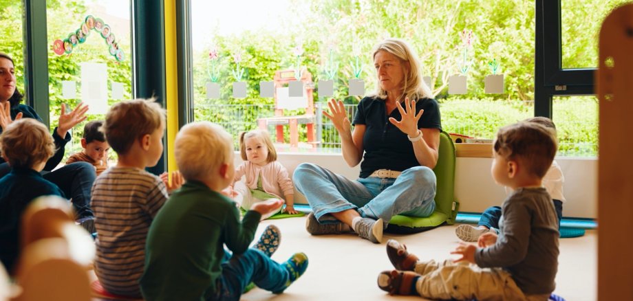Kindergartengruppe mit Erzieherin im Morgensitzkreis