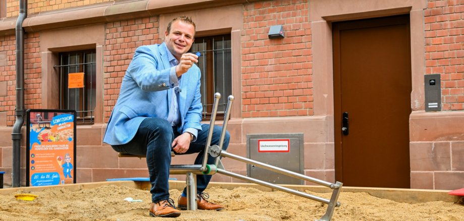 Bürgermeister Benjamin Tschesnok auf dem Schaufelbagger im XXL-Sandkasten
