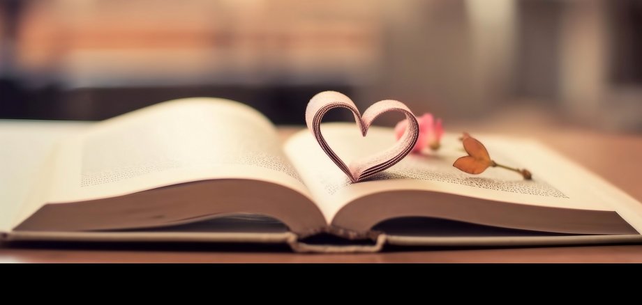 Ein offenes Buch mit Papierherz liegt auf einem Tisch